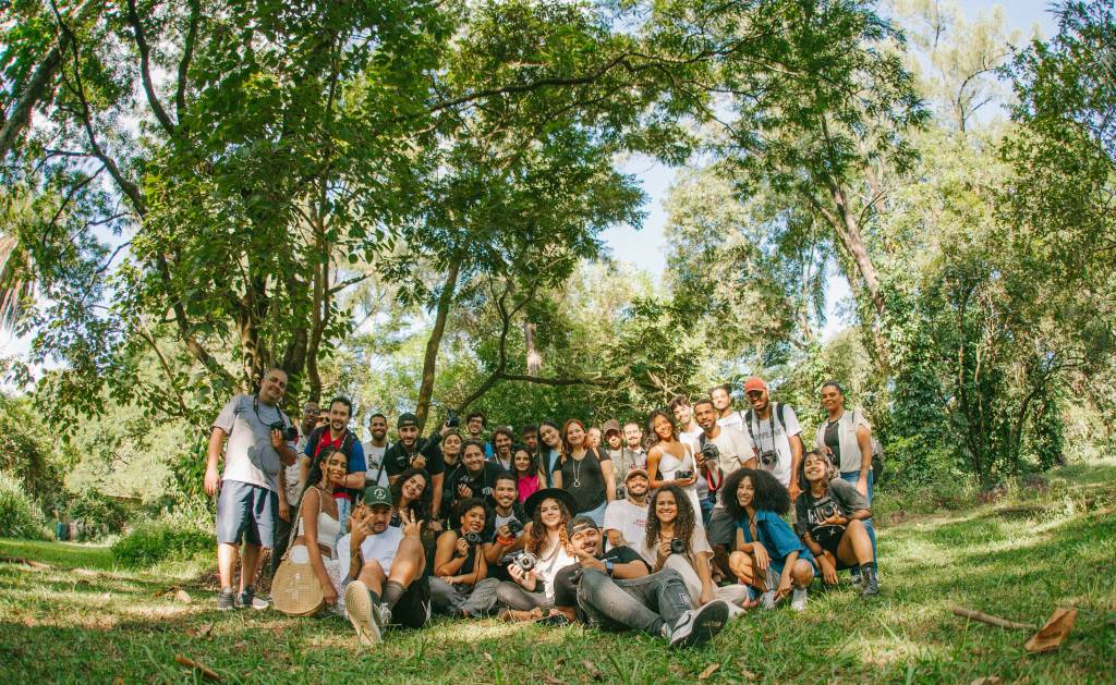 A diverse group of joyful people posing together outdoors in a sunny park setting.